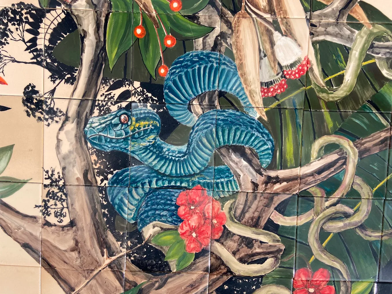 Colourful hand-painted ceramic tile mural with a blue serpent and botanical forms