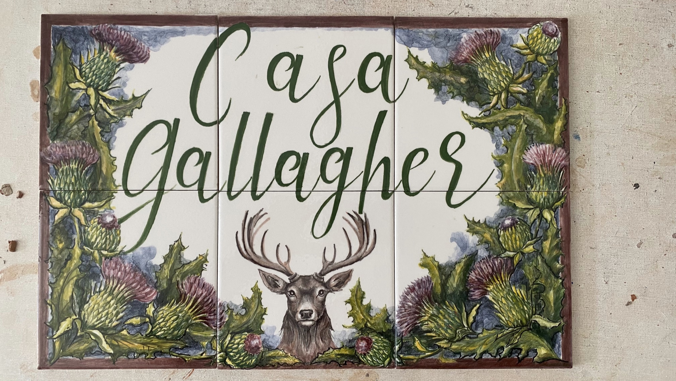 لوحة اسم منزل خزفية مرسومة يدوياً تحمل اسم Casa Gallegos مع نباتات شوكية وأيل عبر ست بلاطات